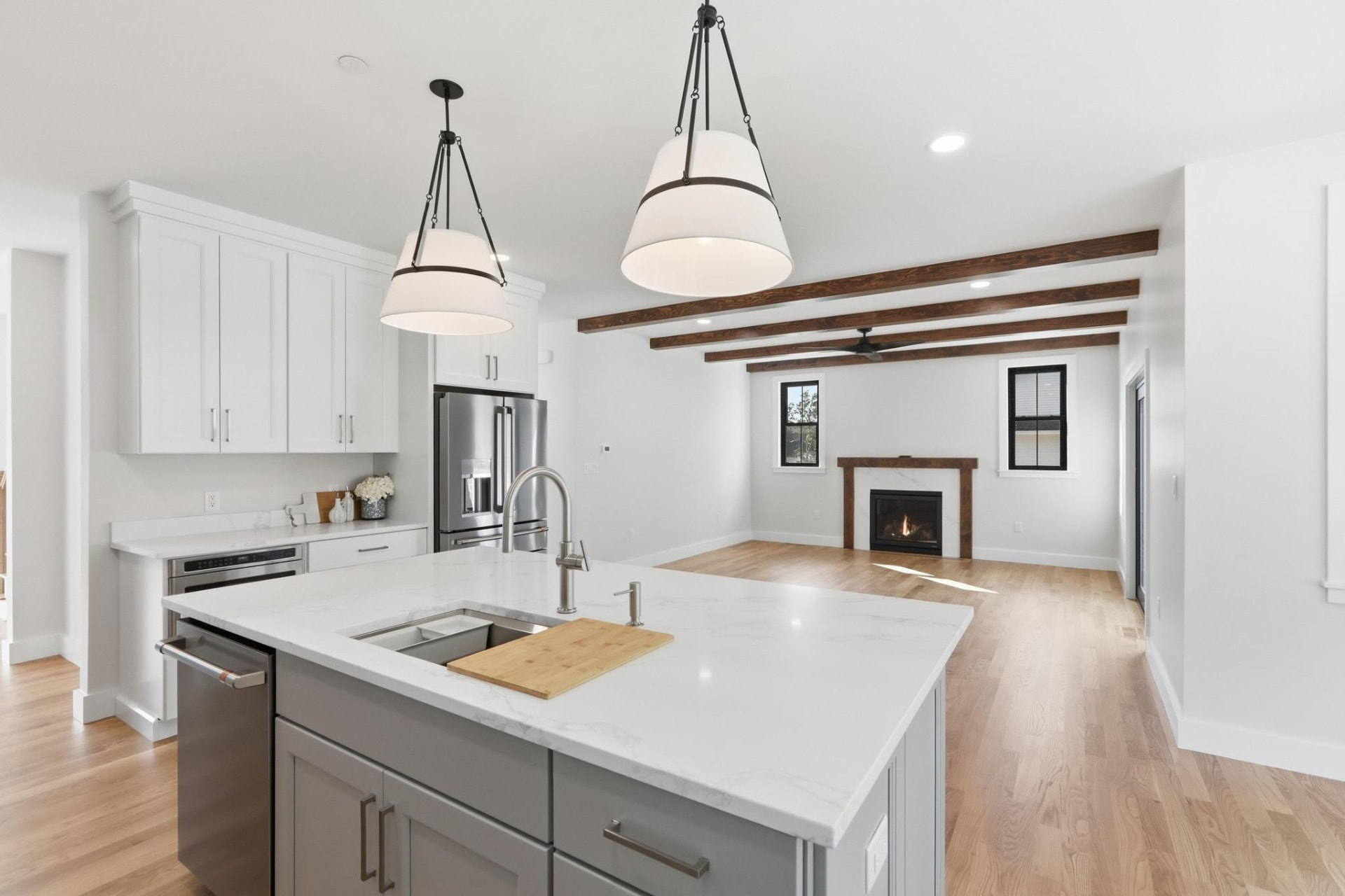 Custom kitchen with white and gray cabinets, marble island, and exposed beams