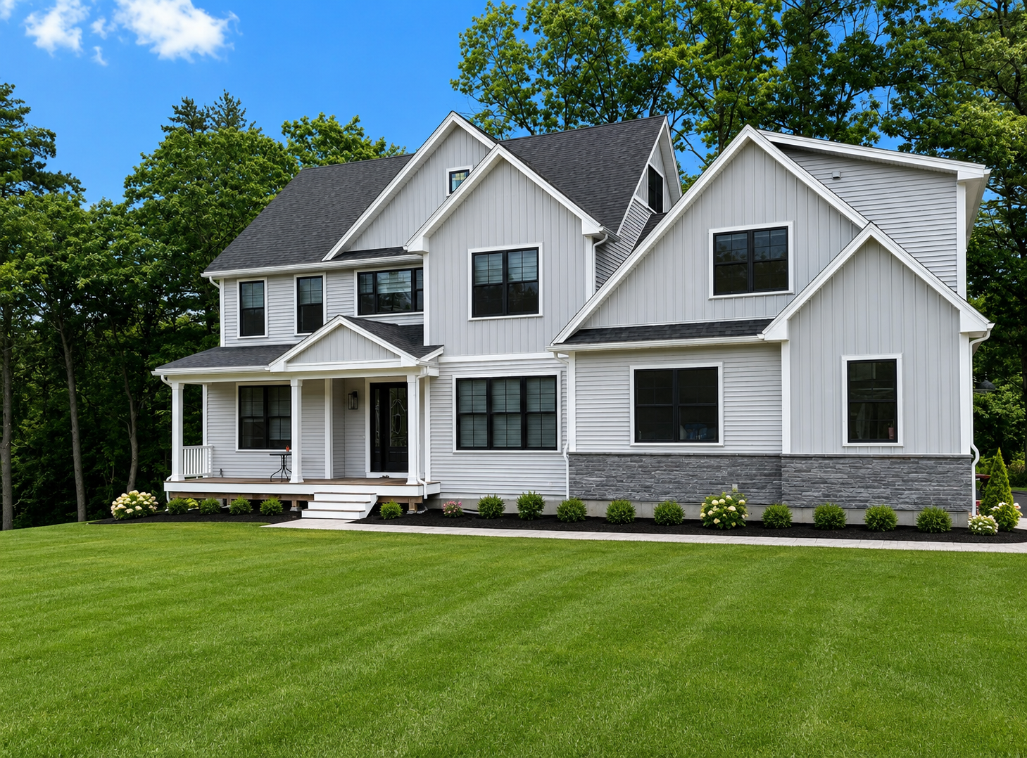 Completed two-story custom home with gray siding, stone veneer, and front porch