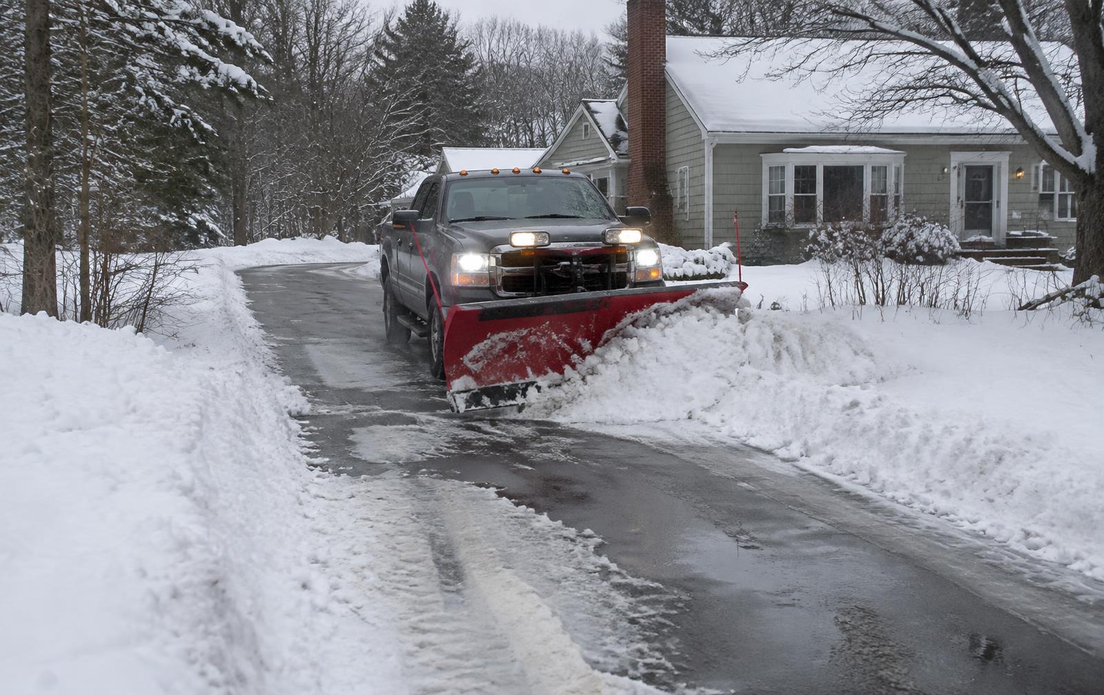 Snow plow truck clearing a residential New England driveway