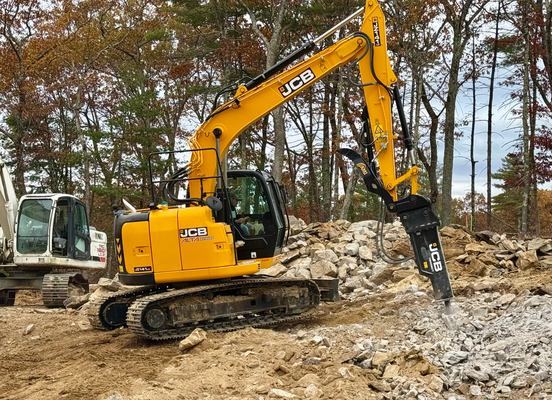JCB excavator breaking rocky ledge at a residential New Hampshire construction site